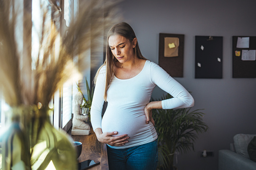 African American pregnant woman feels stomach pain, tries to relax by the window, suffers from abdominal pain, pregnant woman has cramps, copy space