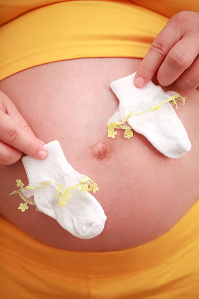 pregnant woman holding baby socks stock photo