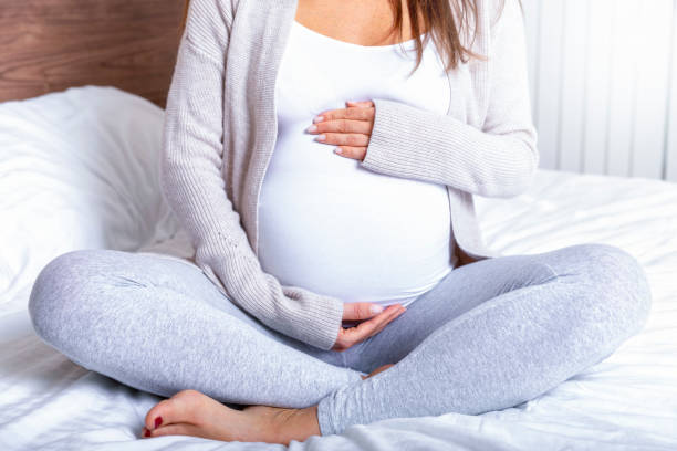 een zwangere vrouw houden van haar baby buik thuis - pregnant stockfoto's en -beelden