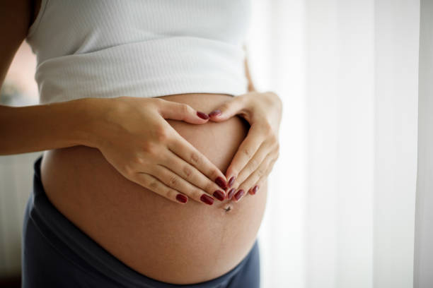 zwangere vrouw houdt haar buik en het maken van een hart vorm - pregnant stockfoto's en -beelden