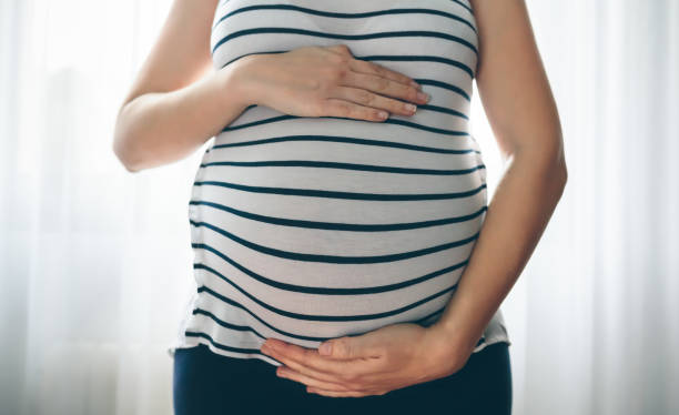 Pregnant woman holding her tummy stock photo