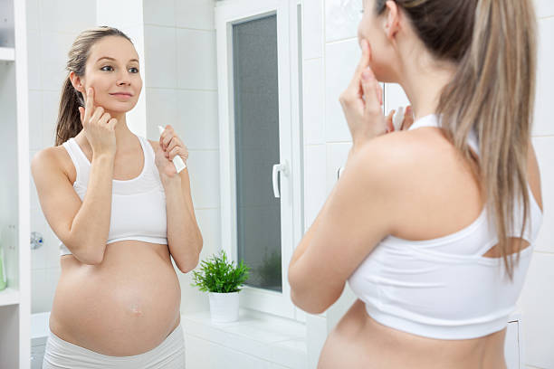 Pregnant woman in bathroom mirror Pregnant woman in looking into bathroom mirror skin during pregnancy stock pictures, royalty-free photos & images