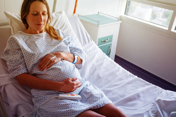 Pregnant woman in hospital bed with catheter hand stock photo