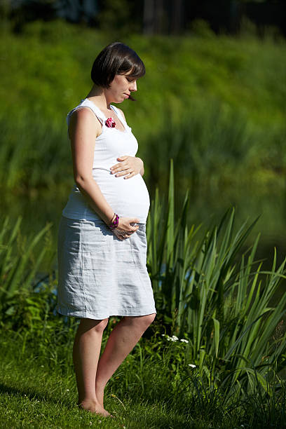 Pregnant woman is walking in the park stock photo