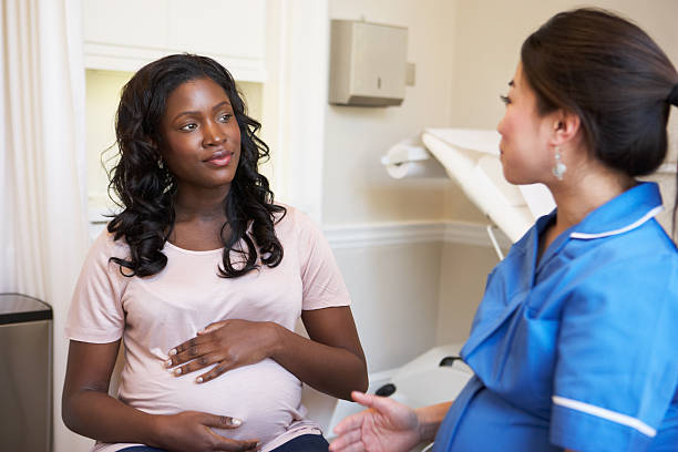 Pregnant Woman Meeting With Nurse In Clinic Pregnant Woman Meeting With Nurse In Clinic to discuss pregnancy obstetrician photos stock pictures, royalty-free photos & images