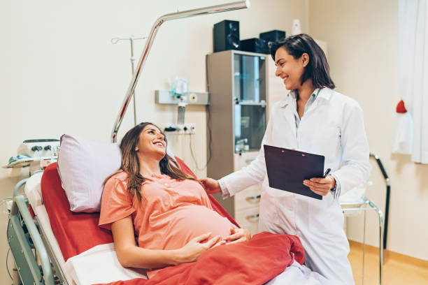 Pregnant woman preparing for delivery Pregnant woman lying down on a hospital bed and talking to a doctor pre pregnancy care stock pictures, royalty-free photos & images