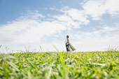 妊娠中の女性は、青い空の下で草の上でリラックス