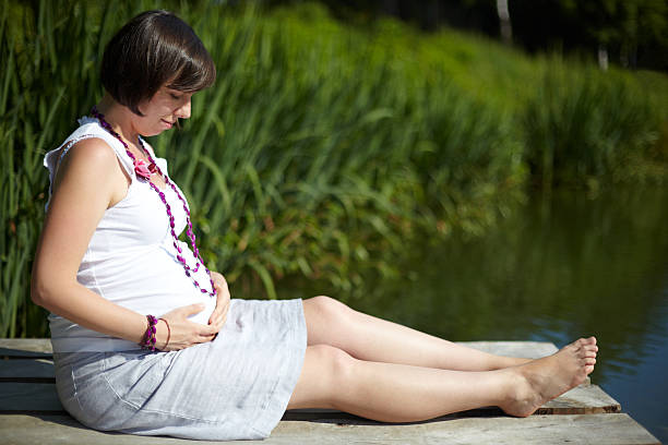 Pregnant woman relaxing at a park stock photo
