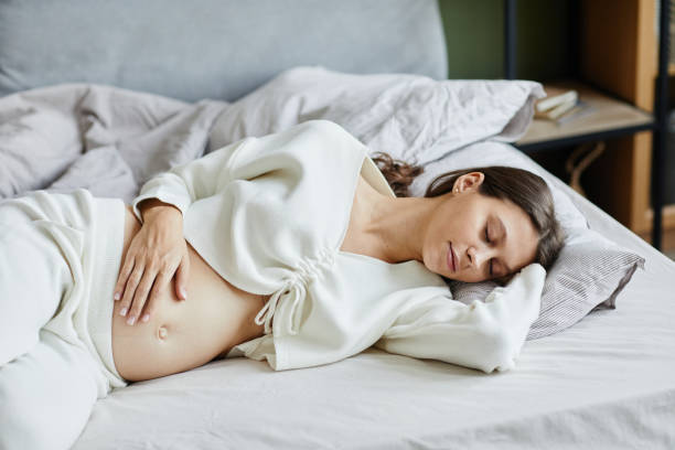 Pregnant woman sleeping in bed at home stock photo