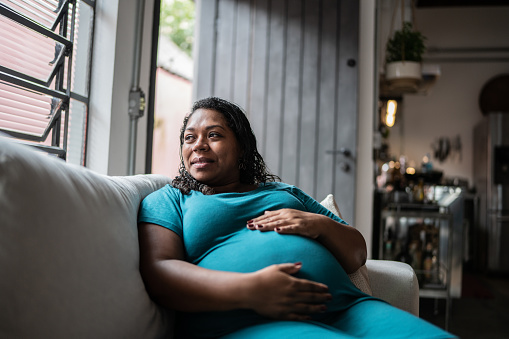 Pregnant woman touching her belly and contemplating at home