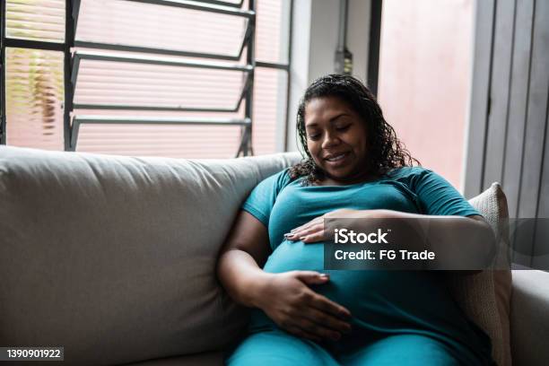 Pregnant woman touching her belly at home