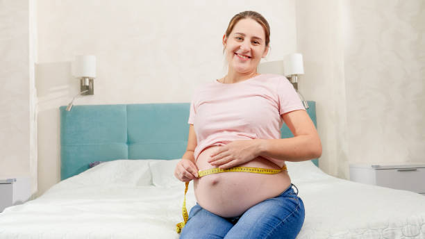Pregnant woman waiting for baby using measuring tape to check her size and body parameters. Concept of pregnant healthcare and healthy nutrition Pregnant woman waiting for baby using measuring tape to check her size and body parameters. Concept of pregnant healthcare and healthy nutrition. pregnant weight stock pictures, royalty-free photos & images