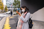 マスクを着用し、路上でスマートフォンを使用して妊娠中の女性