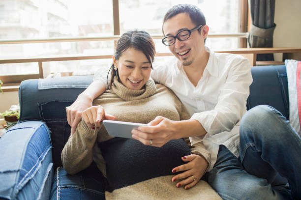 Pregnant woman with her husband in room Happy expecting pregnant asian couple mid adult couple stock pictures, royalty-free photos & images