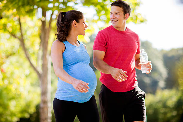 pregnant woman with husband exercising. - pregnant couple outside stockfoto's en -beelden