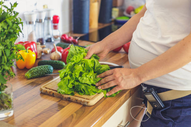 Pregnant woman with insulin pump preparing healthy food in the kitchen stock photo