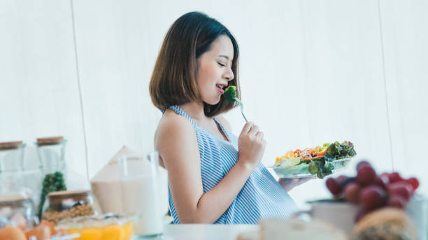 Pregnant women eat vegetables salad delicious and happy. stock photo
