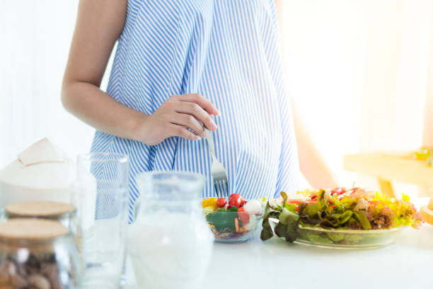 Pregnant women Put on a blue dress. She is eating breakfast salad.
For the health and for the baby in her belly.
Contains coconut, milk and salad dressed on the table. stock photo