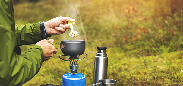 preparing food outdoors on gas burner. camping cooking equipment. copy space
