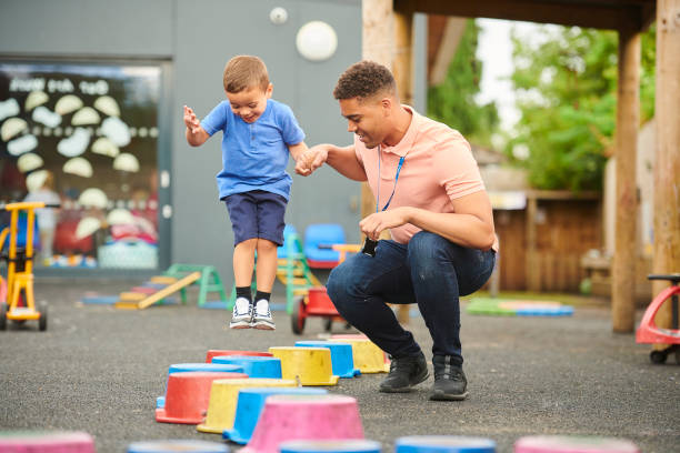 pre-school stepping stones nursery worker with child in playground recess stock pictures, royalty-free photos & images