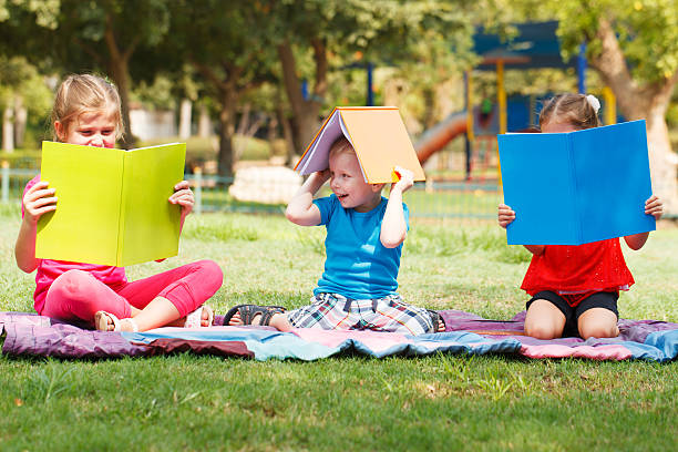 Preschoolers reading outdoors stock photo