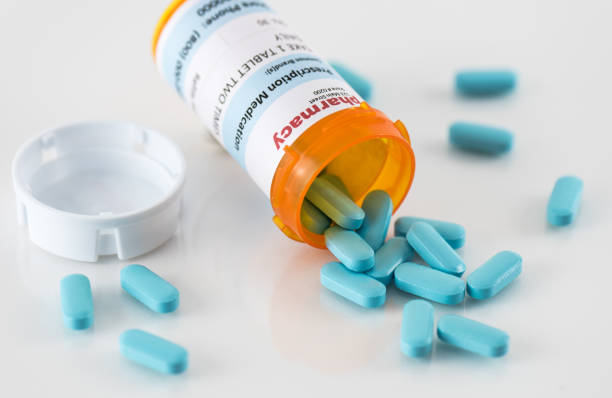 Prescription Bottle with Spilled Blue Pills Prescription bottle with spilled blue pills on reflective surface generic drug stock pictures, royalty-free photos & images
