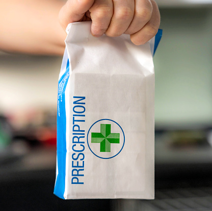 Close-up of a person holding a bag containing prescription medicine.