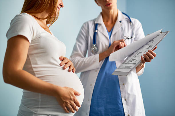 Prescriptions Pregnant female looking at paper with medical prescriptions held by her therapeutist obstetrician photos stock pictures, royalty-free photos & images