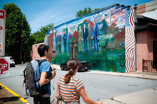 Washington DC, USA - June 16, 2012: A young man and woman walk past a mural of several U.S. Presidents (from Eisenhower to Obama), painted on the wall of Mama Ayesha's restaurant in the Adams Morgan area of Washington DC.