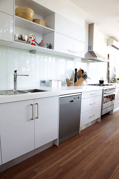A prestige clean crisp white modern kitchen and wood floor stock photo