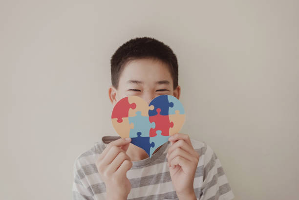 Preteen boy holding puzzle jigsaw,  child mental health concept, world autism awareness day, teen autism spectrum disorder awareness concept stock photo