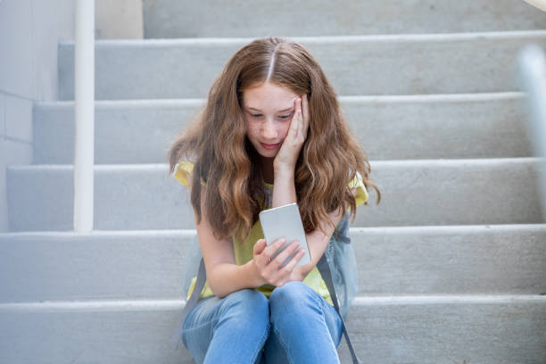 Preteen middle school girl is sad after being cyberbullied on social media stock photo