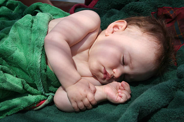Pretty baby sleep on a bench with towels stock photo
