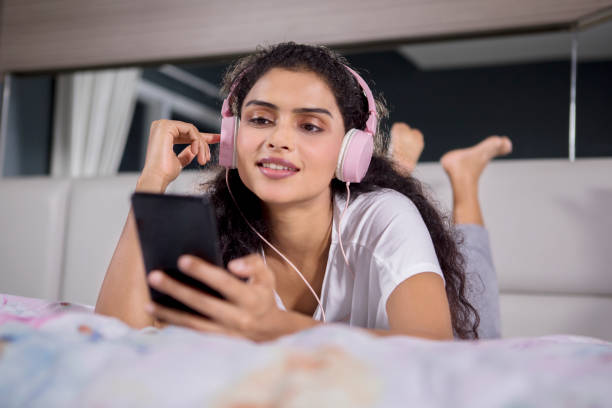 Pretty girl hearing music on the bed stock photo