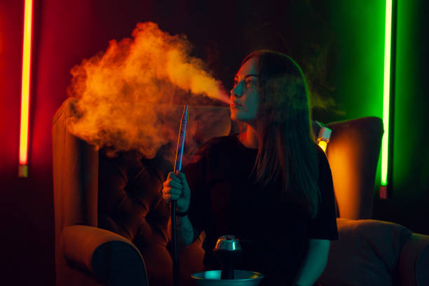 mooi meisje in een zwart t-shirt is het roken van een waterpijp uitademen van een rook op een luxe nachtclub - sisha stockfoto's en -beelden