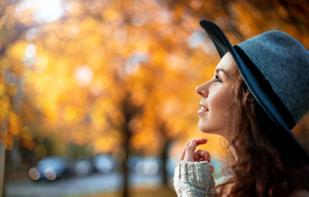 Photo of Pretty girl in hat standing on colorful autumn leaves background