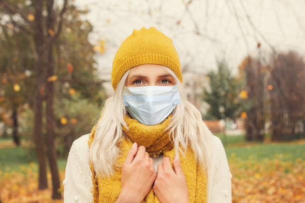 Pretty girl in medical face mask walking outdoors Pretty girl in medical face mask walking outdoors allergy medicine stock pictures, royalty-free photos & images