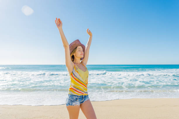 Pretty girl with arms outstretched enjoying the breeze on the beach stock photo