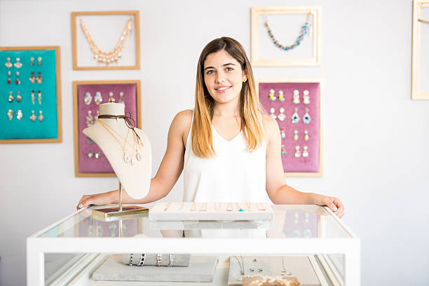 Pretty Hispanic woman owns a jewelry Portrait of a beautiful young Hispanic woman standing behind a counter in her jewelry shop and smiling store clerk selling jewelry stock pictures, royalty-free photos & images