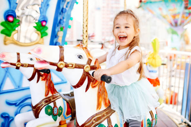 Pretty kid on carousel horse. Cute girl is riding attraction. Fun celebration stock photo