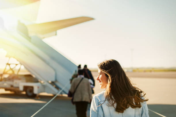 Pretty woman getting in to plane Woman tourist passenger getting in to airplane at airport, walking from the terminal to the plane. passenger stock pictures, royalty-free photos & images