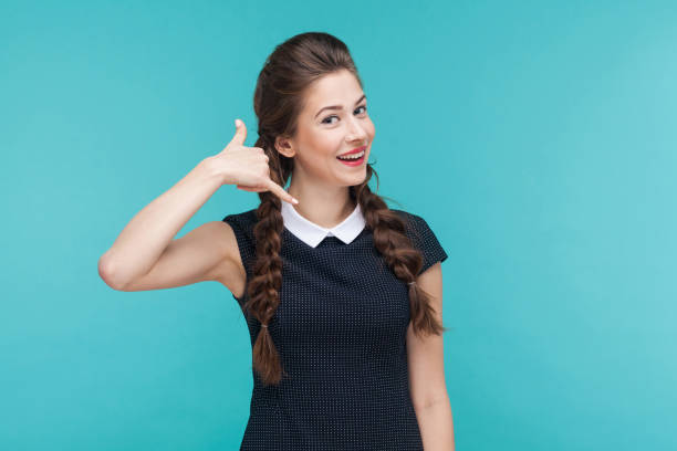 Pretty woman looking at camera, smiling and showing phone sign. Call me! Pretty woman looking at camera, smiling and showing phone sign. Studio shot, blue background big smile emoji stock pictures, royalty-free photos & images