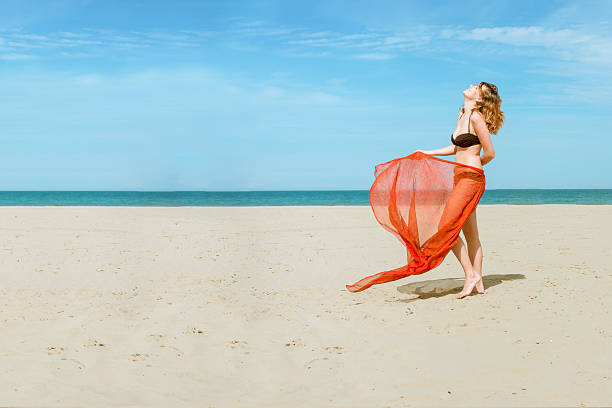 pretty woman on beach wearing silk fabric sarong stock photo