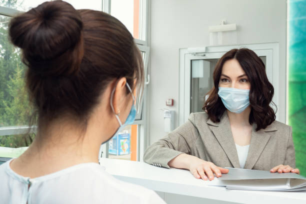 Pretty woman patient talks to administrator near counter stock photo