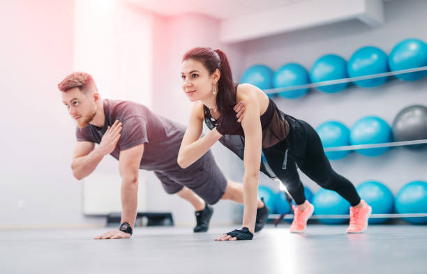 Pretty young couple doing exercises together in the light gym. stock photo