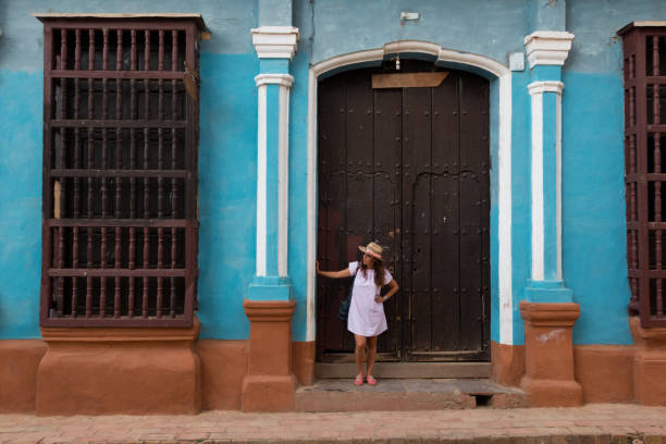 A pretty young woman with hat located at the door of an old colonial house in the colonial town of Trinidad (Cuba). stock photo