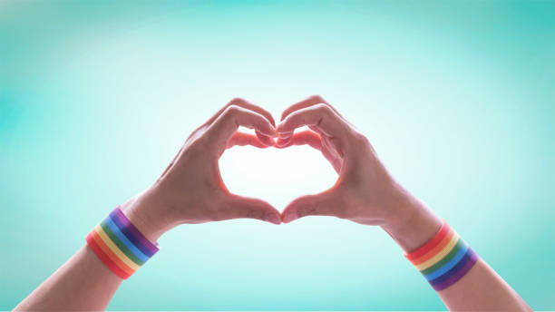 mês do orgulho lgbt com pulseira de fita de bandeira do arco-íris em lgbtq pessoas coração-forma mãos para o dia internacional contra a homofobia e transfobia - homofobia - fotografias e filmes do acervo