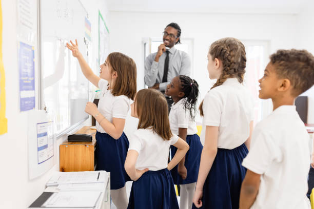 Primary School Teacher and students In Classroom stock photo