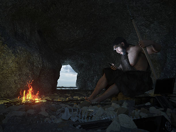 primitive man siting in the cave with smartphone concept illustration - fire caveman imagens e fotografias de stock