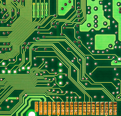 Close up of an unpopulated printed circuit board showing tracks and gold connecting pins.